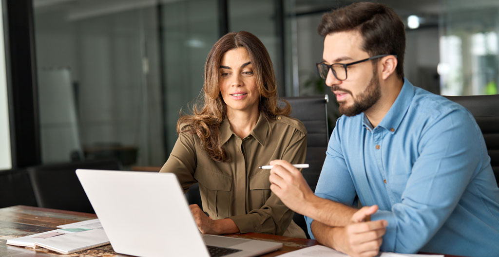 Deux professionnels en formation échangeant autour d'un ordinateur portable